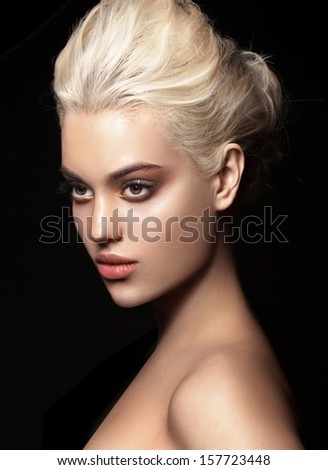 Young model with big lips and make up, blonde, black background Fashion look