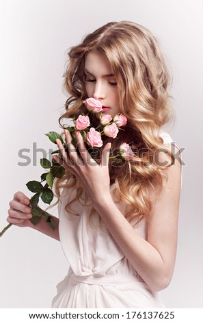 Beautiful young model with pink rose, bright makeup and manicure. Tender portrait studio shot