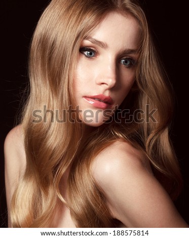 Close-up portrait of beautiful model with long blond hair on black background