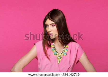 Fashion model with classic make up. Flowers. Spring look. Perfect skin, brunette hair. Pink background.