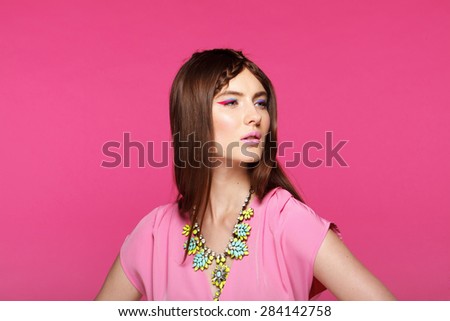 Fashion model with classic make up. Flowers. Spring look. Perfect skin, brunette hair. Pink background.