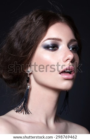 Young model with big lips and make up, smoky eyes, brunette, black background Fashion look. Jewelry.