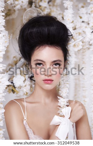 Portrait of a beautiful fashion bride, sweet and sensual. Wedding make up and hair. Flowers background. Art modern style. Blue eyes. Brunette.