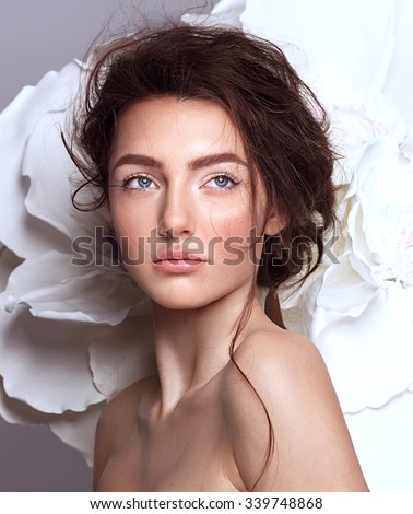 Portrait of a beautiful fashion brunette bride, sweet and sensual. Wedding make up and hair. Flowers background. Art modern style. Blue eyes.