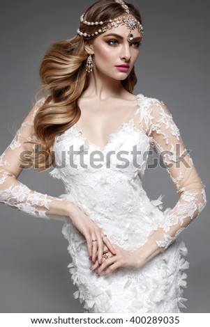 Fashion model bride with long flowing blonde hair and make up. Studio shot. Wedding dress. Pink lips. Jewelry. Middle east style woman.