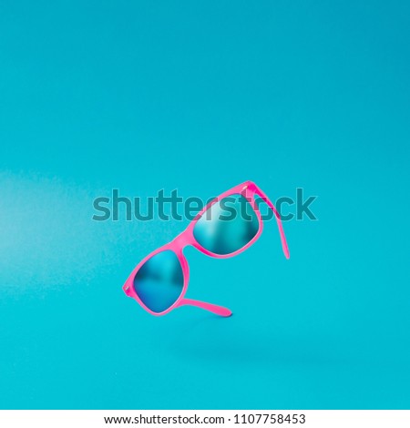 Pink sunglasses on pastel blue background. Minimal summer concept. Semi flat lay.