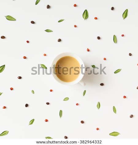 Colourful bright pattern made of  leaves, berries and coffee beans with coffee cup.