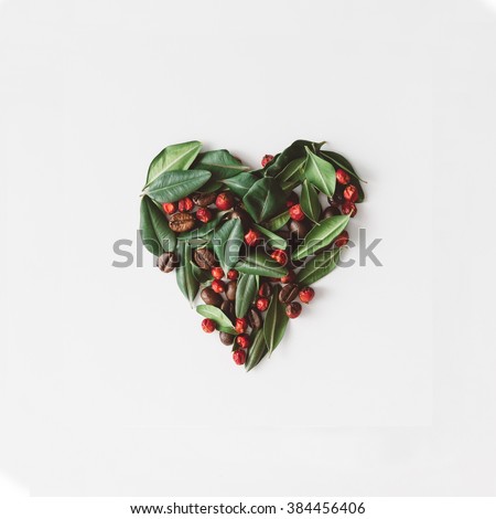Heart symbol, made of leaves berries and coffee beans, broken in half.