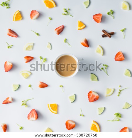 Colorful pattern made of citrus fruits, leaves and strawberries with cup of coffee or tea.
