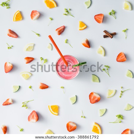 Colorful pattern made of citrus fruits, leaves and strawberries with smoothie.
