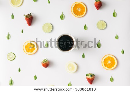 Colorful pattern made of citrus fruits, leaves and strawberries with cup of coffee