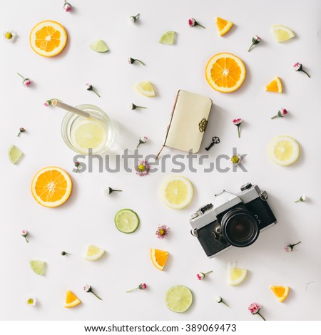 Colorful pattern made of orange, lemon, lime and flowers with lemonade and vintage camera and notebook.