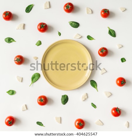 Colorful pizza ingredients pattern made of cherry tomatoes, basil and cheese on white background. Cooking concept.