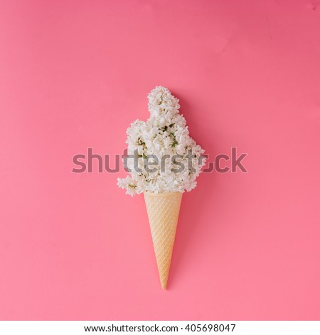 Lilac flower in ice cream cone on pink background. Minimal concept. Flat lay.