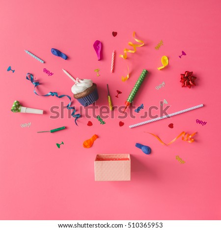 Gift box with colorful party items on pink background. Flat lay.