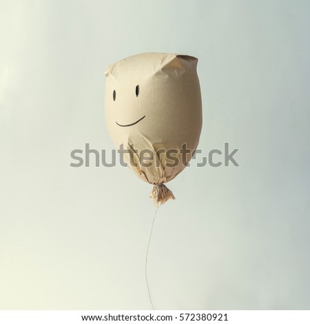 Paper bag balloon with smiley face emoji  on white background. Creative minimal concept.