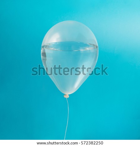White balloon with water on pastel blue background. Creative minimal concept.
