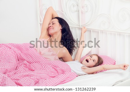 young mother and daughter wake up in the morning in bed