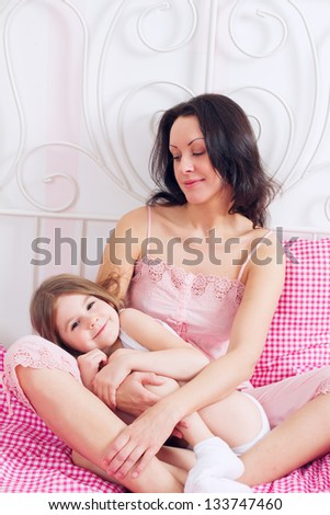 Young Mother and daughter embracing on bed