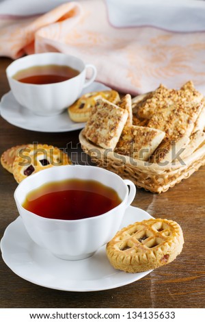 two cups of tea and biscuits with jam