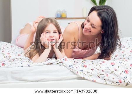 happy mother and daughter playing in bad