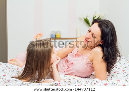 happy mother and daughter playing in bad