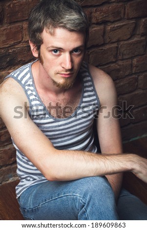 young man sitting on the floor against a brick wall