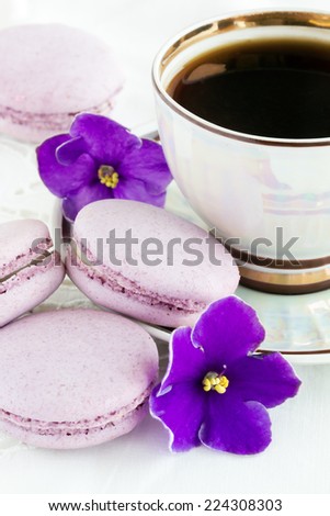 violet macaroon with violet flowers and a cup of coffee