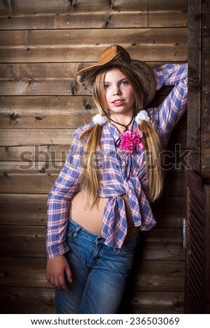 Cute teenager girl in a cowboy hat on a ranch posing in studio