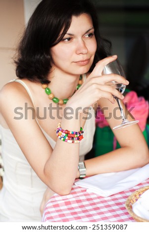 Beautiful young woman sitting in a summer cafe and drinking water