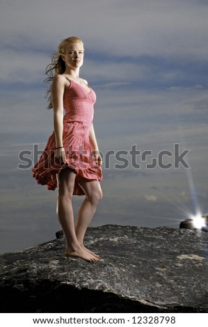 stock photo Barefoot girl in a dress lit against an evening sky