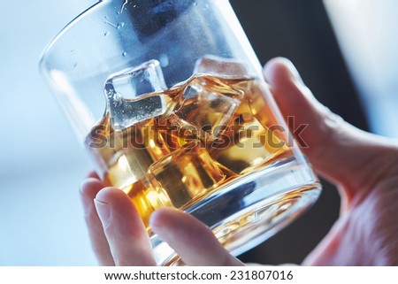 glass of whiskey with ice in his hand