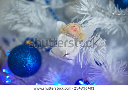 Christmas toys in the form of an angel hanging on the tree next to the balls and beads