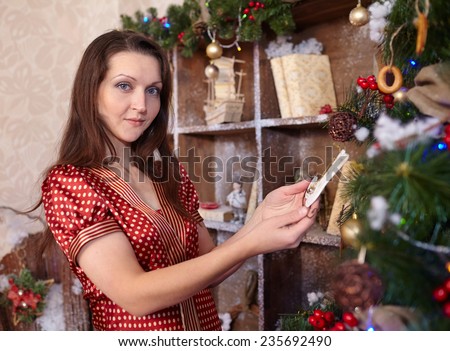 young beautiful woman in burgundy dress dresses up Christmas tree