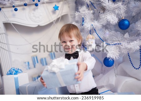 boy five years gives Christmas gift sitting near the Christmas tree