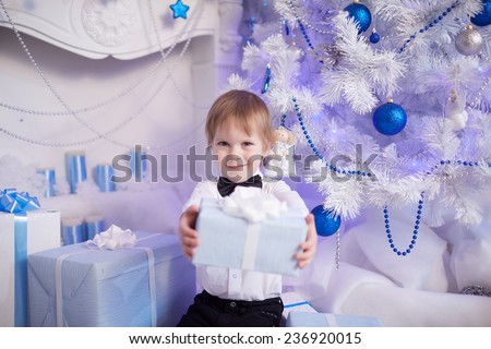 boy five years gives Christmas gift sitting near the Christmas tree