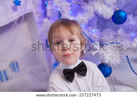 boy five years in anticipation of a gift, sitting near the Christmas tree