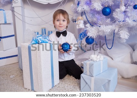 boy five years in anticipation of a gift, sitting near the Christmas tree, holding a blue balloon