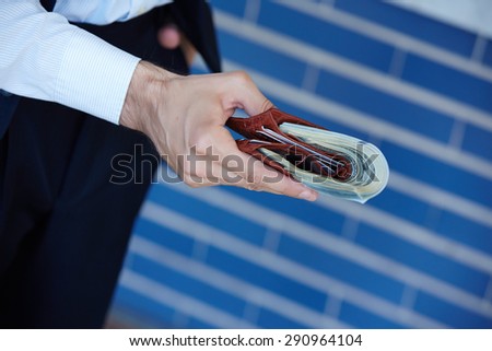 man holding a purse with money closeup