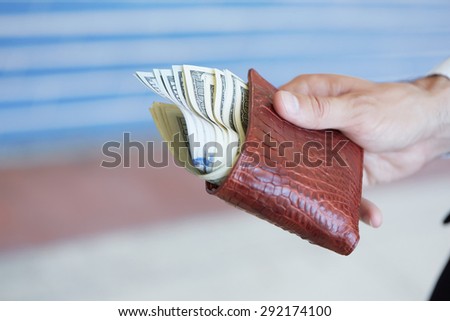 man holding a purse with money closeup