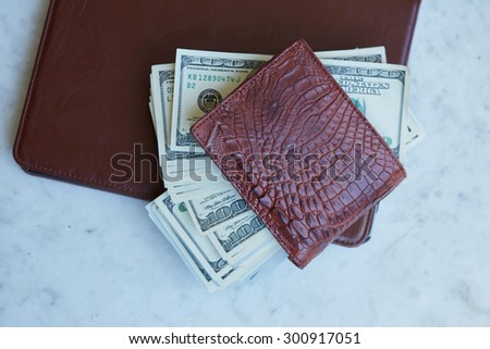 tablet on the table in a leather pouch and a leather purse with money