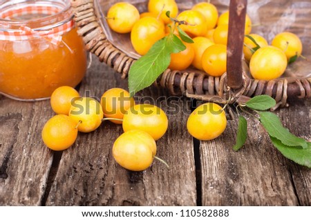 freshly harvested yellow plums in an old fruit basket on wooden table