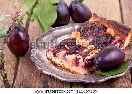 Plum cake with fresh plums on a plate on wooden table