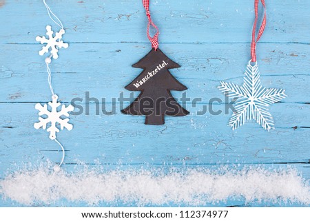 Christmas decoration on a blue wooden board with white snow, snowflakes, ice crystals and a slate christmas tree, wish list for christmas