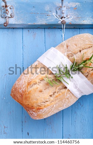 Fresh Ciabatta (Italian bread) is hanging headlong on a hook on a blue wooden board, ciabatta bread ready for sale