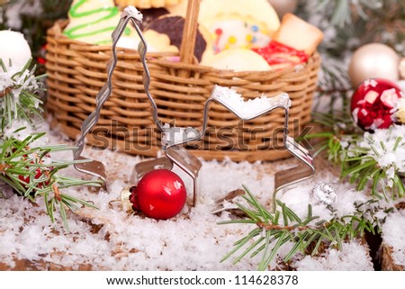 christmas cookies in a basket with red and white christmas balls, snow and cookie cutters