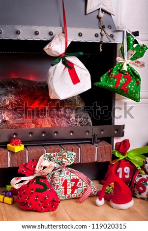 bags as part of an Advent calendar hanging from a mantel or fireplace, decorated for Christmas with fire glowing
