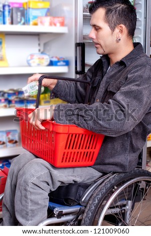 young man in wheelchair in Barrier-free supermarket is looking for some food in the shop, disabled young man is shopping