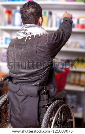 young man in wheelchair in Barrier-free supermarket is looking for some food in the shop, disabled young man is shopping