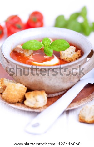 fresh diet tomato soup with basil thyme and raw tomatoes with bread pieces in a bowl on white background, ready to eat